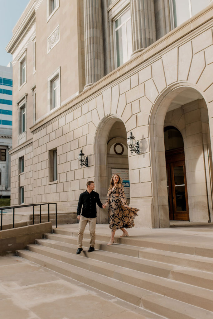 Couple walks down stairs in downtown Kansas City during Fall Engagement Shoot