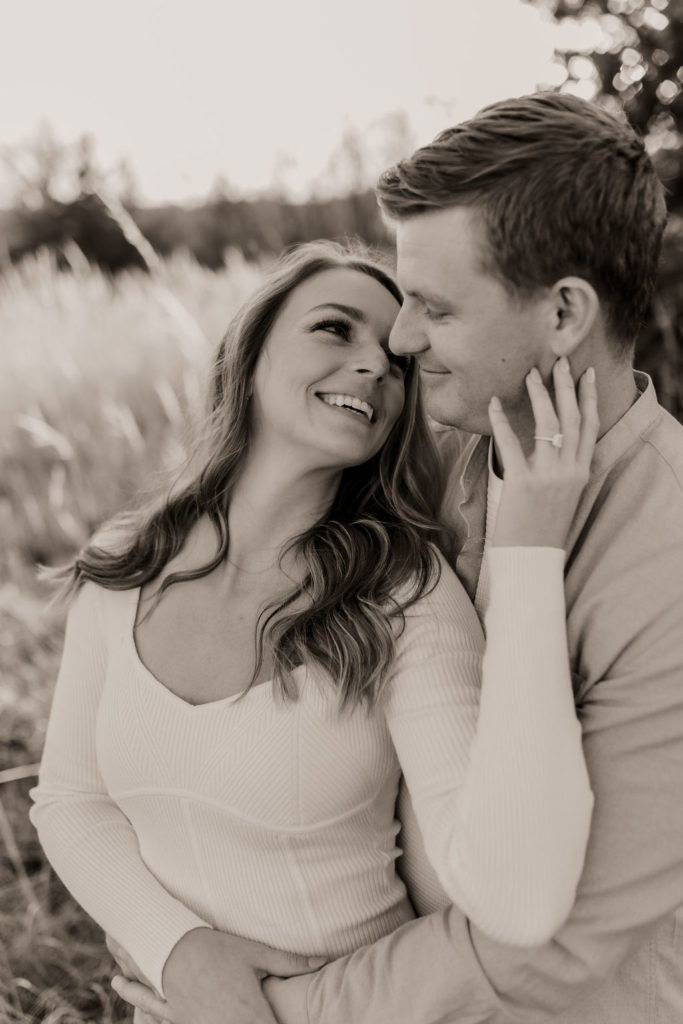 Black and White Photo of Couple Embracing during intimate engagement shoot, highlighting engagement ring