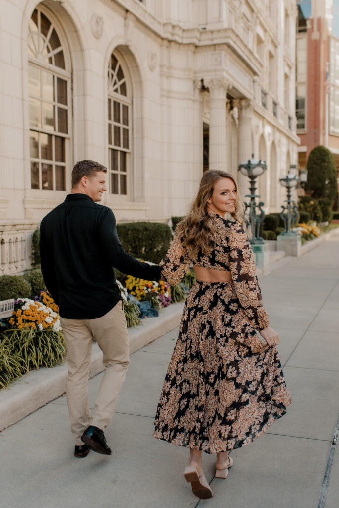 Engagement photo of couple walking in downtown Kansas City