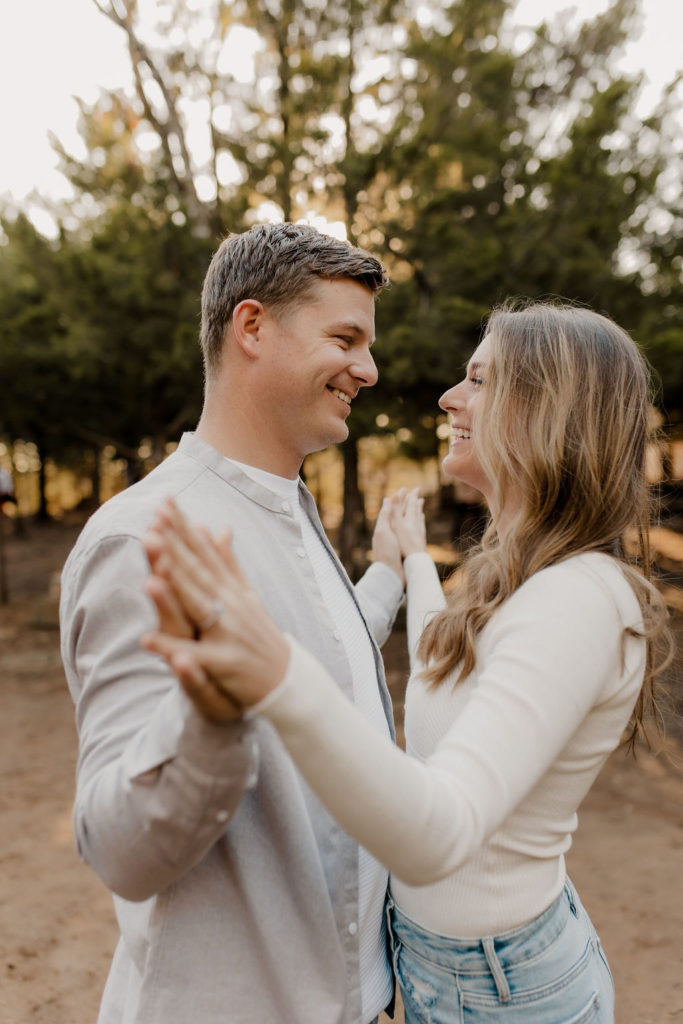 Couple clasps hands in fall engagement photo at Shawnee Mission Park