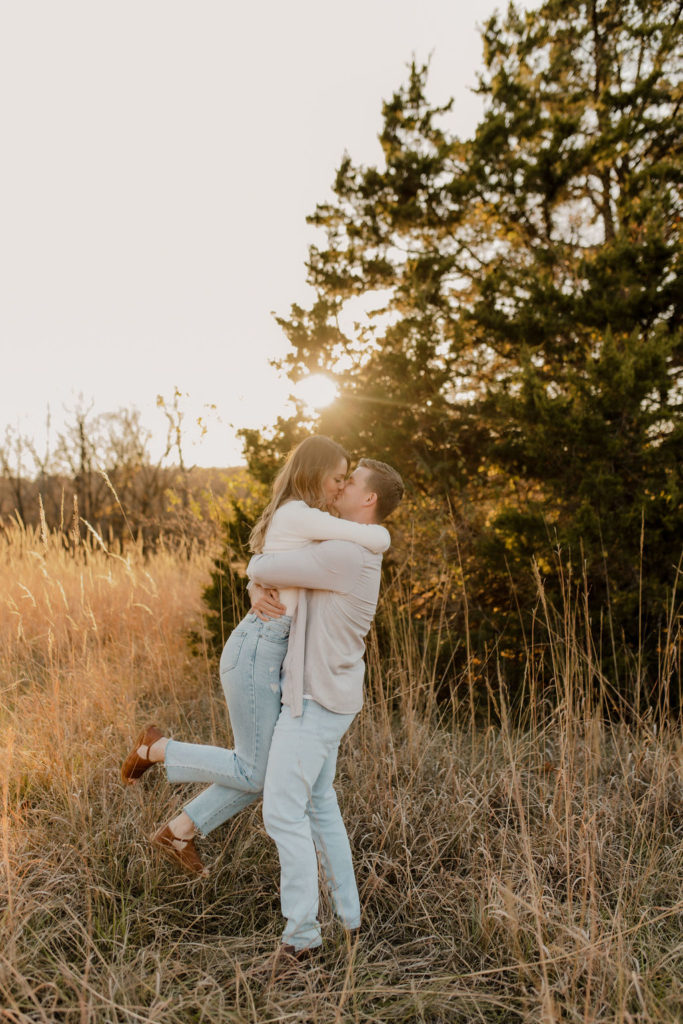 Fall engagement photo of couple kissing in park