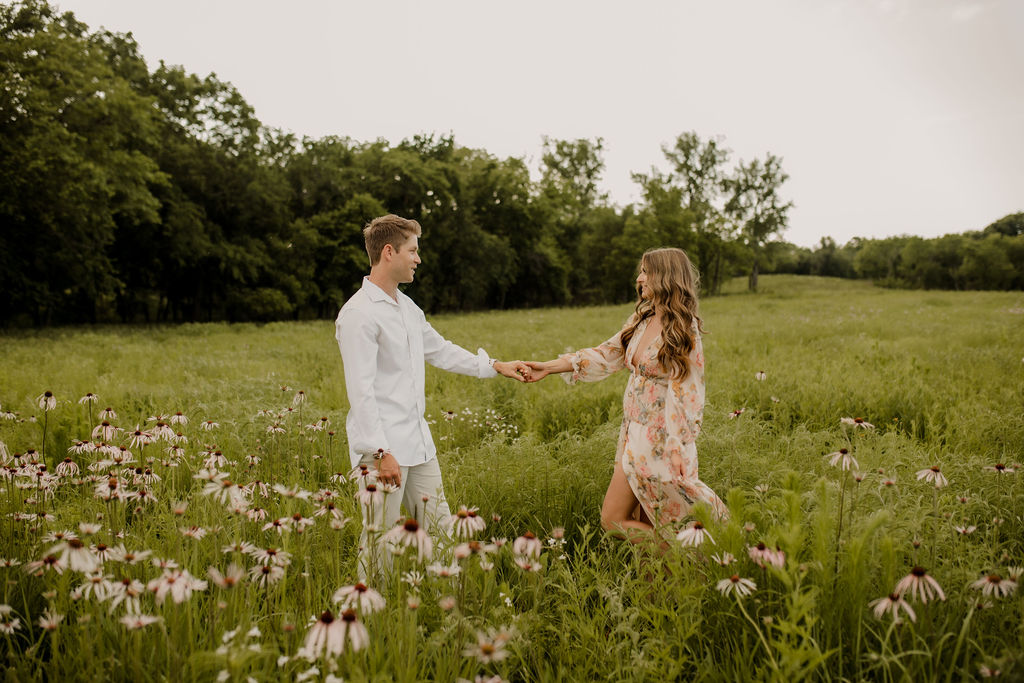 Engaged couple holding hands in wildflower field