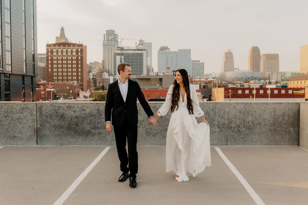 Engaged Couple Holds Hands with Downtown KC Skyline in background